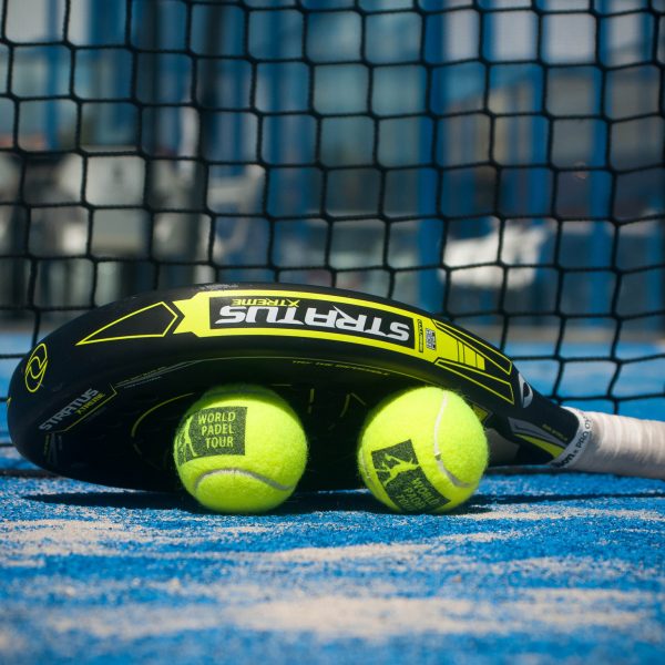 Padel racquet and two balls on a court