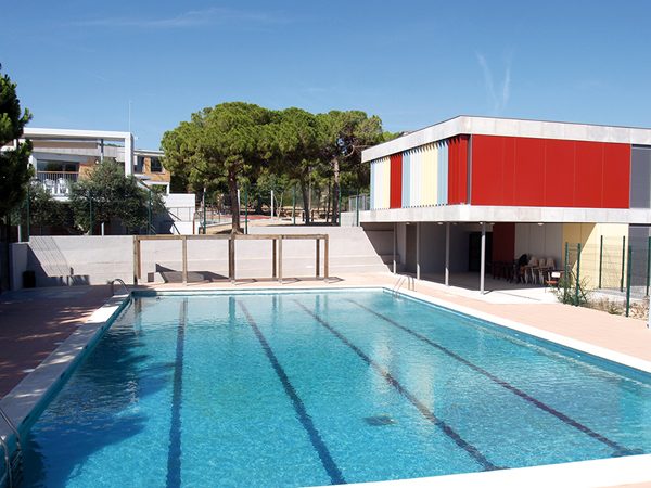 Swimming pool of the Artur Martorell summer camp accommodation and the building with a colourful façade on the right