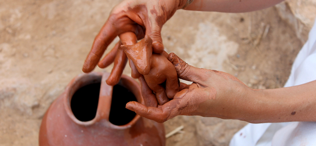 Dues mans agafant una figura feta amb fang
