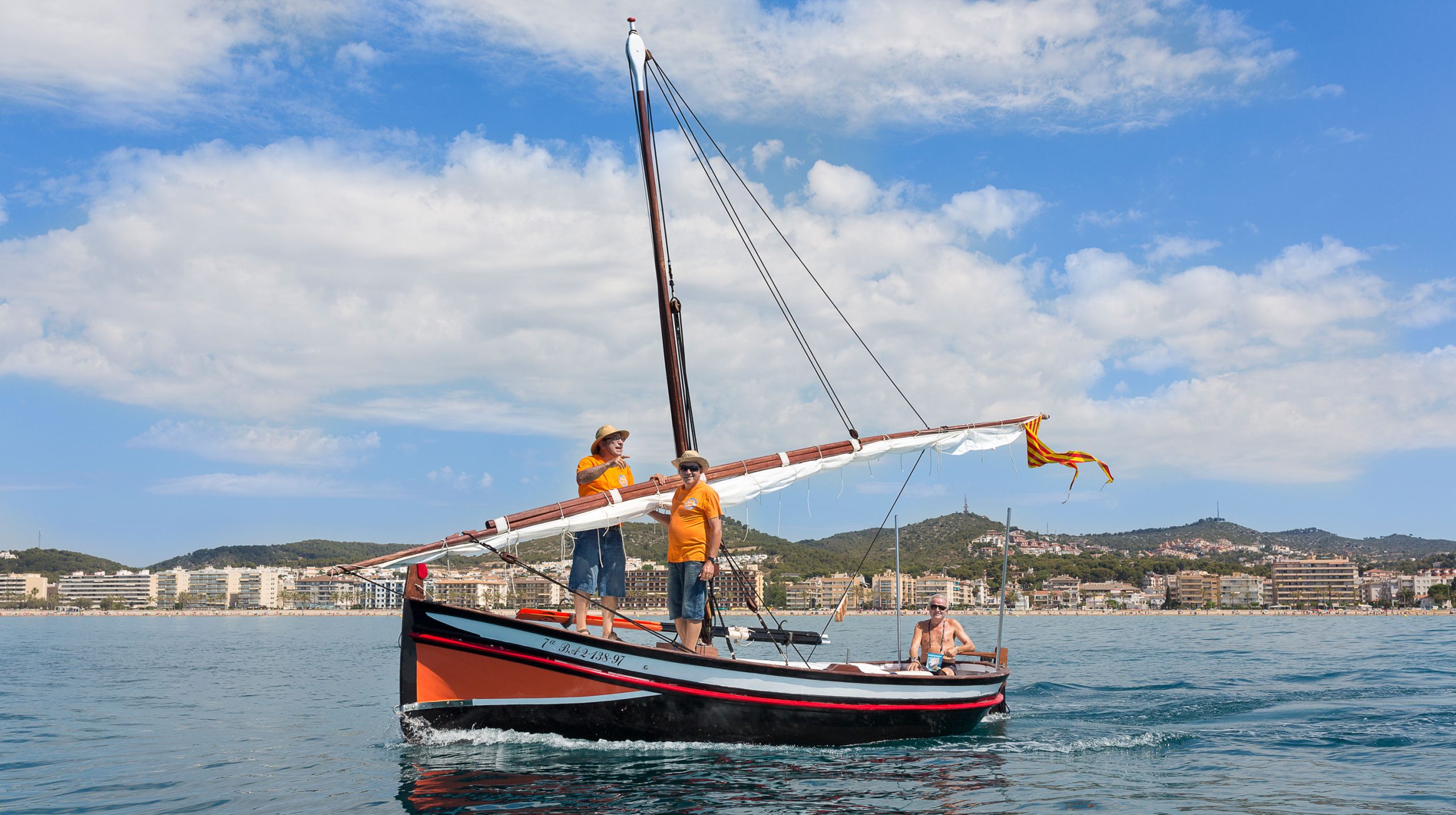 Three people on a lateen-rigged sailboat