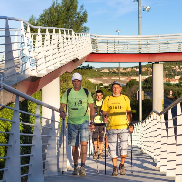Group of people Nordic walking across the bridge to Segur