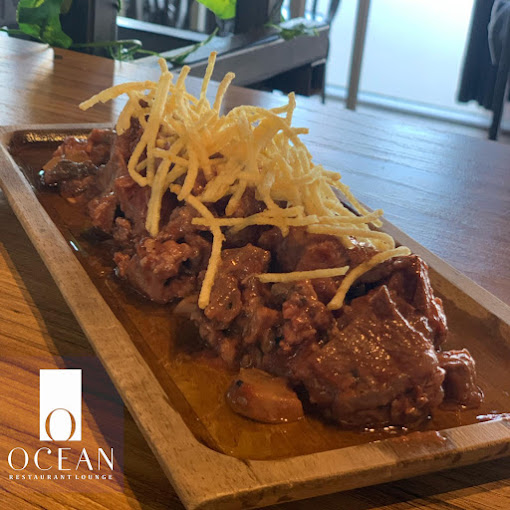 Plat de carn amb salsa amb patates fregides per sobre de Ocean Restaurant Lounge